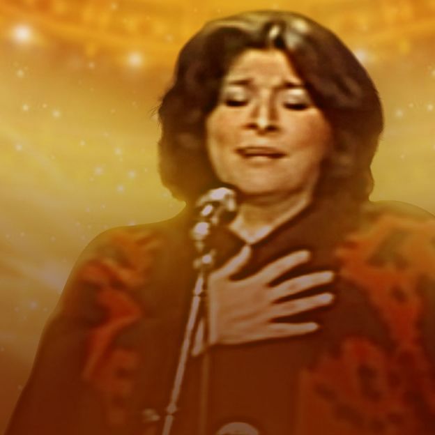 A cantora Mercedes Sosa canta ao vivo com os olhos fechados no centro da imagem