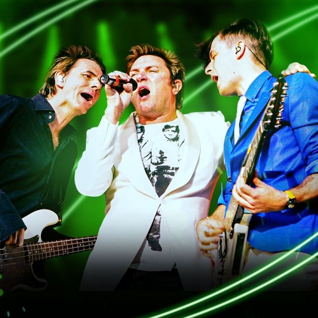 Três integrantes da banda Dura Duran cantam lado a lado no centro da imagem