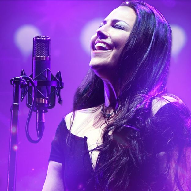 Vocalista da banda Evanescence canta com os olhos fechados no centro da imagem