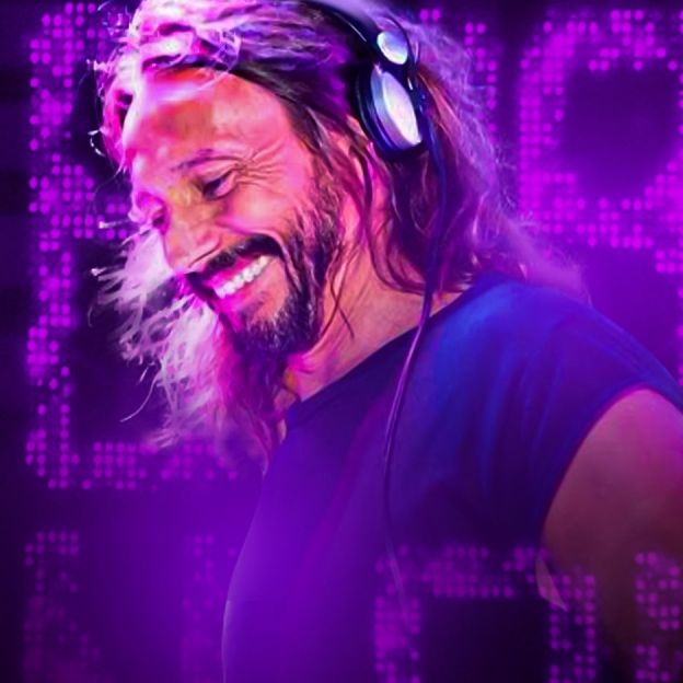 O DJ Bob Sinclar posa no centro da imagem com fones de ouvido na cabeça